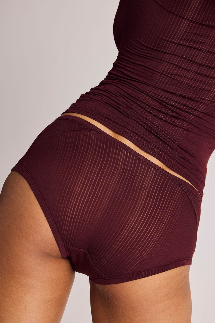 Close-up of a model wearing ribbed high-waisted boy shorts in a deep burgundy color.